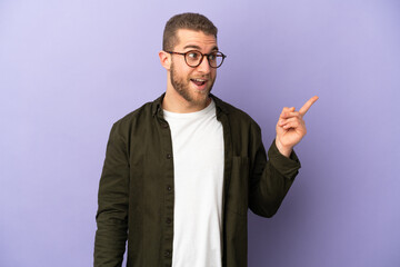 Young handsome caucasian man isolated on purple background intending to realizes the solution while lifting a finger up