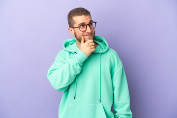 Young handsome caucasian man isolated on purple background thinking an idea while looking up