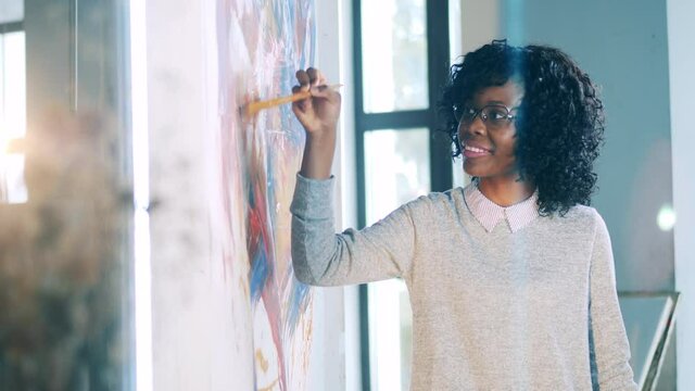 African-american woman is happily drawing on a canvas