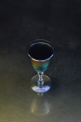 black cocktail drink in vintage iridescent glass on muted gold brass table 