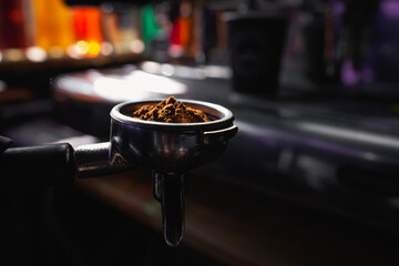 Natural ground coffee in tempera. Behind the tempera with coffee is a large coffee machine.