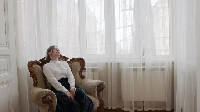 young girl sits in a chic vintage chair and enjoys herself and life
