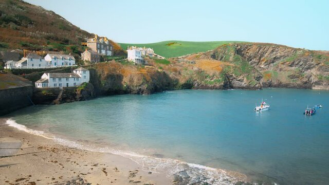 Port Isaac, small fishing village, Atlantic coast of north Cornwall, England. Porthysek - rocky scenic views with crystal clear transparent waters, green lands and beautiful old English houses in 4K.