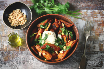 Baked carrot bowl with white cheese, cilantro and peanuts. Healthly food. Vegetarian lunch.
