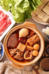 Personal spicy hot pot with pork, tofu,  mushrooms and green leaves 
