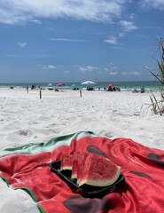 Select focus of watermelon on beach towel on white sand beach