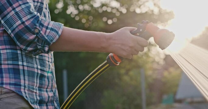 The gardener's hand pours a garden hose with a diffuser