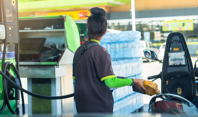 Staff hold yellow fuel nozzle to refilling the motorcycle in the gas  station, Refilling the...