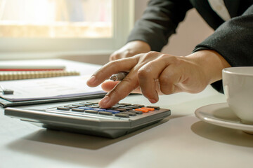 Close-up of woman using a calculator to do financial accounting, working, and saving ideas.