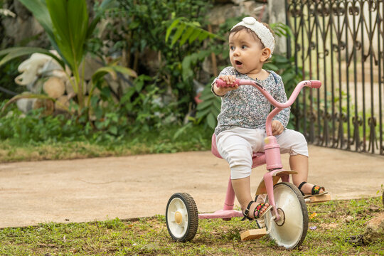 Cute toddler child, boy, playing with tricycle in park and eating apple, kid riding bike on sunset