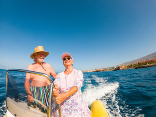 Beautiful and cute couple of seniors or old people in the middle of the sea driving and discovering...