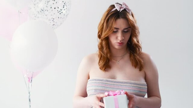 Bad gift. Disappointed pregnant woman. Holiday fail. Baby shower party. Sad tummy lady feeling regret throwing away gift box light balloons isolated white background copy space.