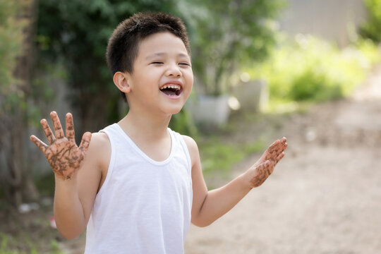 Happy Asian children playing outside with dirty hands