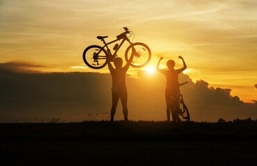 Fototapeta na wymiar Young Couple in love fun and happy riding mountain bike after covid-19 coronavirus outbreak. End of the coronavirus outbreak. Silhouette cycling man and woman riding mountain bike at sunset time.