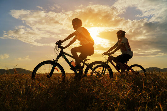 Young Couple in love fun and happy riding mountain bike after covid-19 coronavirus outbreak. End of the coronavirus outbreak. Silhouette cycling man and woman riding mountain bike at sunset time.