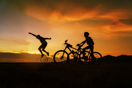 Young Couple in love fun and happy riding mountain bike after covid-19 coronavirus outbreak. End of the coronavirus outbreak. Silhouette cycling man and woman riding mountain bike at sunset time.