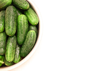 Cucumbers in bowl on side of white background 