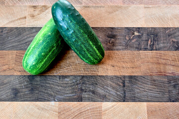 Two cucumbers on butcher block board