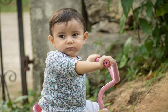 Cute toddler child, boy, playing with tricycle in park and eating apple, kid riding bike on sunset