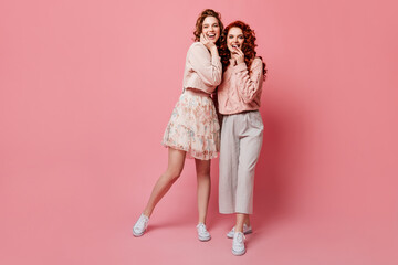 Two laughing girls in white gumshoes looking at camera. Wonderful young ladies having fun on pink...