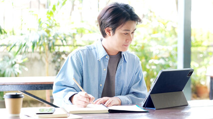 Online studying class, Student man hand writing on notebook while using digital tablet for e learning, Adult male university, college student study online course at home, education, Work from home