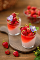 Creamy dessert with strawberry jelly in a glass with strawberry berry decor on a wooden background