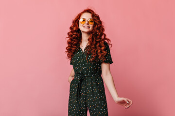 Blithesome ginger girl looking at camera with smile. Studio shot of charming red-haired lady posing on pink background.