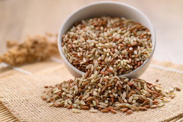 Organic Thai highland brown rice grain in a bowl and pouring (Cargo rice, Loonzain rice or Husked rice), Healthy food