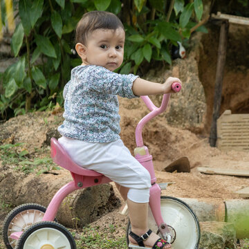Cute toddler child, boy, playing with tricycle in park and eating apple, kid riding bike on sunset