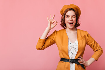 Pleasant caucasian girl showing okay sign. Front view of beautiful french lady posing with hand on hip isolated on pink background.