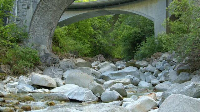 Water flowing around stones under the bridge. Creek in the mountains. Switzerland.