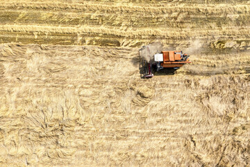 Fototapeta na wymiar agricultural harvester machine working in the ripe wheat field. aerial top view from flying drone