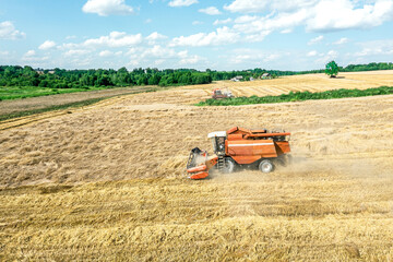 harvest time. combine harvester working on a wheat field. summer landscape under blue sky with...