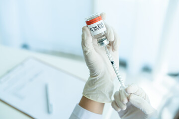 Doctor preparing a dose of vaccine for injection at patient left arm close up with copyspace. 