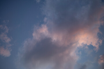 Blue sky with gray and pink puffy clouds