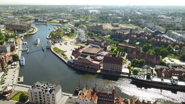 Aerial view of  banks Nova Motlawa river in Old Town of Gdansk, tour ferries and big ship near the quay, Polish Baltic Frederic Chopin Philharmonic, city Ferris wheel, Hotel KROLEWSKI
