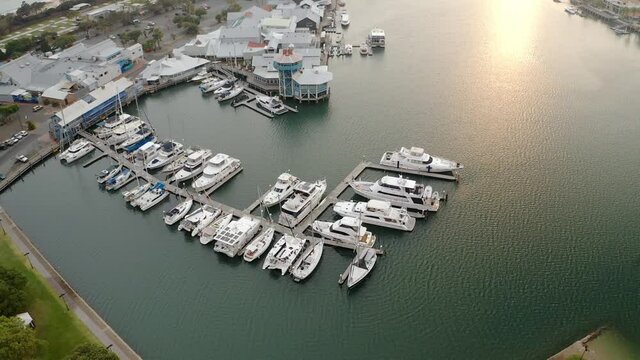 Luxury Yachts And Boats Moored On Jetty By Mooloolaba River With Seafood Restaurant At Sunrise In QLD, Australia. - aerial