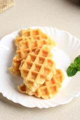 Plain Croffle Croissant Waffle on White Palte, Cream Table with Mint Leaf. This Snack Popular in South Korea