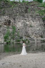 The bride in a white wedding dress on the bank of a mountain river.