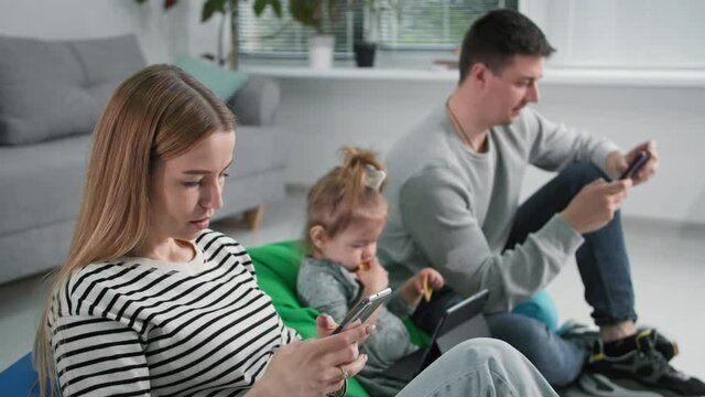 family problems, young married couple with small female child uses modern technology and text messages on social networks while spending time at home