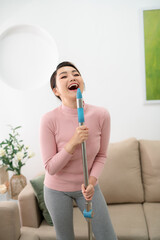 happy asian woman in headphones with mop and bucket cleaning floor and singing at home