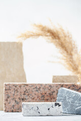 Composition of travertine and granite blocks and pampas grass. Abstract modern background. Natural materials.
