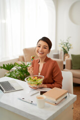 Woman has healthy business lunch in modern office interior.