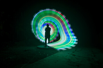 One person standing alone against a Colourful circle light painting as the backdrop	