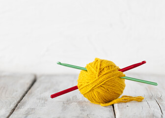 yellow yarn ball and crochet hook on white wood table 