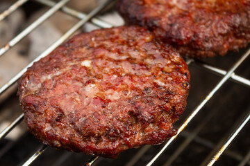 Beef burgers on a barbeque in summer sunlight