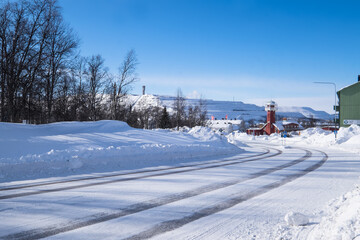 KIRUNA, SWEDEN - MARCH 15 2020: The old firestation of Kiruna in winter, now used as a regional TV station.  In the background the factories of the LKAB, a large Swedish iron mining company