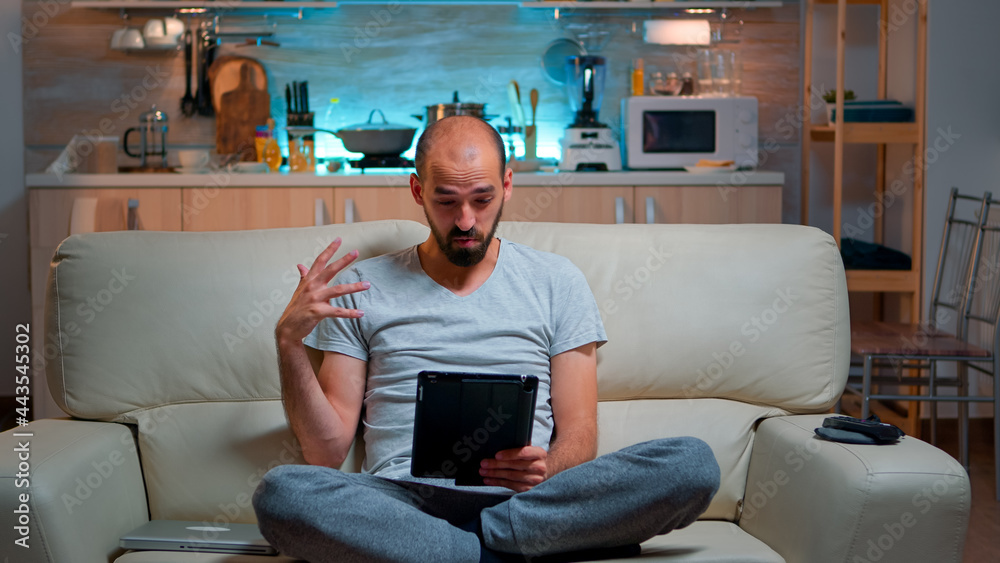 Poster focused man having online meeting videocall on tablet computer speaking using videoconference online