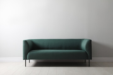 Comfortable green sofa near white wall indoors. Interior design