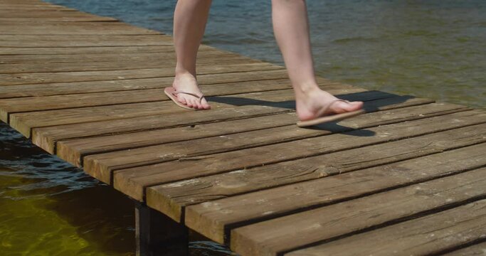 close up of a woman with white legs walking on a wooden bridge